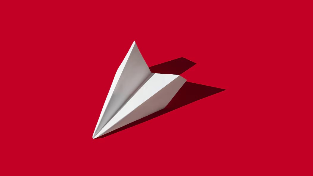 Imagen de avión de papel sobre fondo rojo